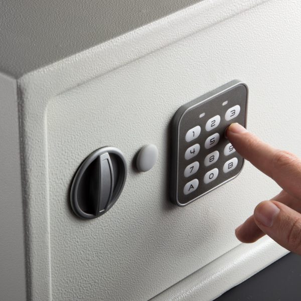 the hand opens a combination lock on the safe, a light safe on a dark background